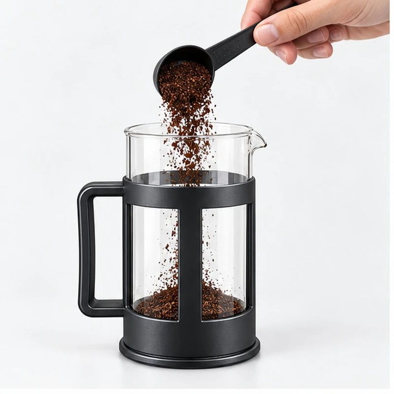 Café molido cayendo dentro de la prensa francesa abierta.