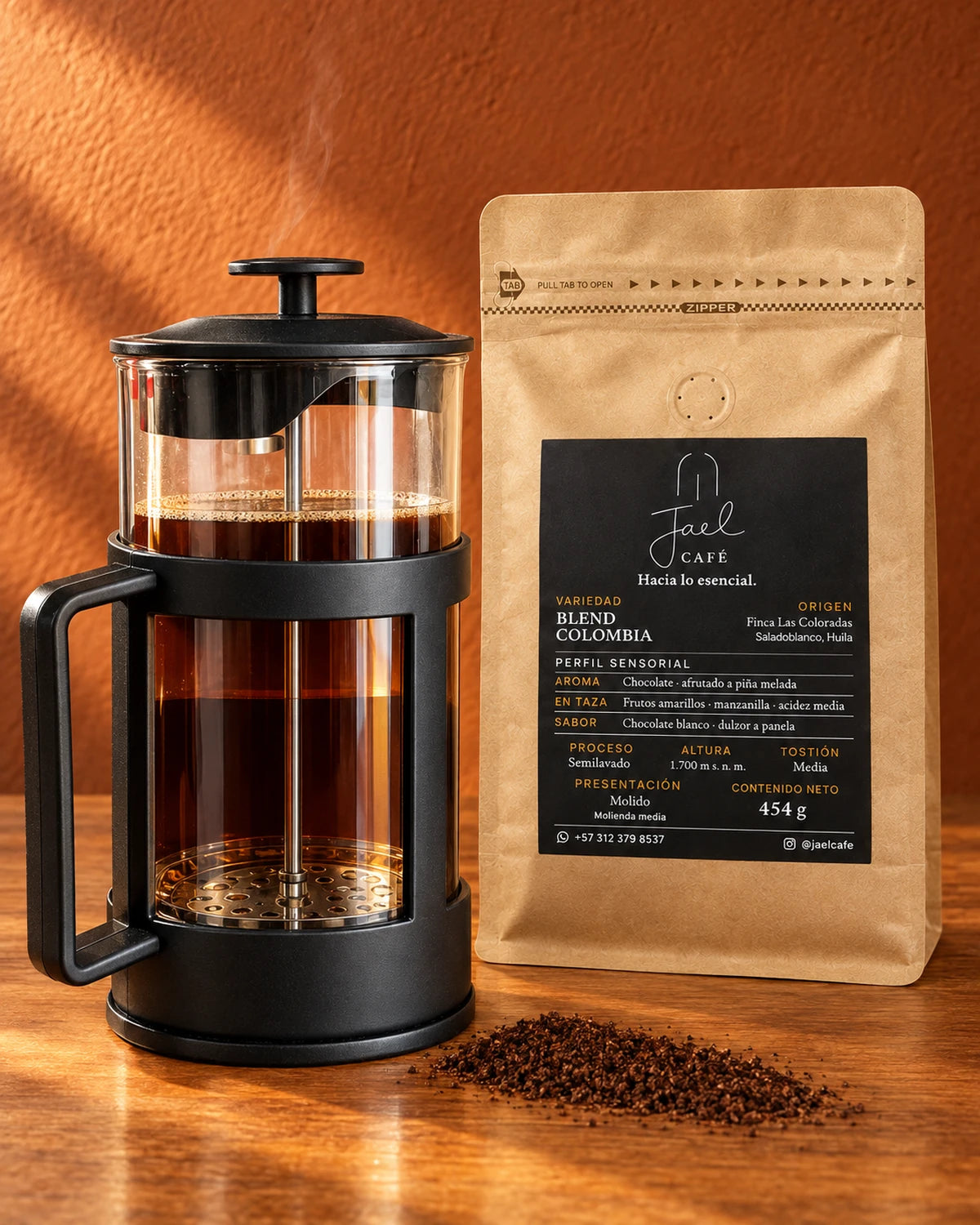 Prensa francesa negra con café recién preparado junto a una bolsa de café JAEL sobre una mesa de madera.